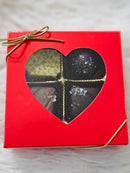 Red gift box with heart-shaped window displaying four chocolate pieces on a white background 